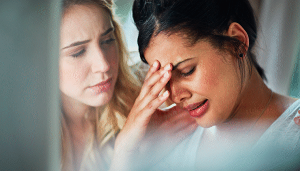 Mujer agobiada por la depresión es consolada por su amiga.