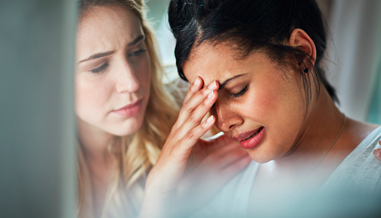 Mujer agobiada por la depresión es consolada por su amiga.